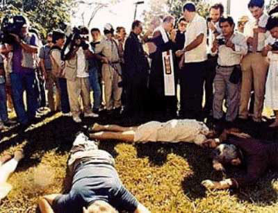 Un grupo de personas observan con terror los cuerpos yacentes de los jesuitas asesinados.