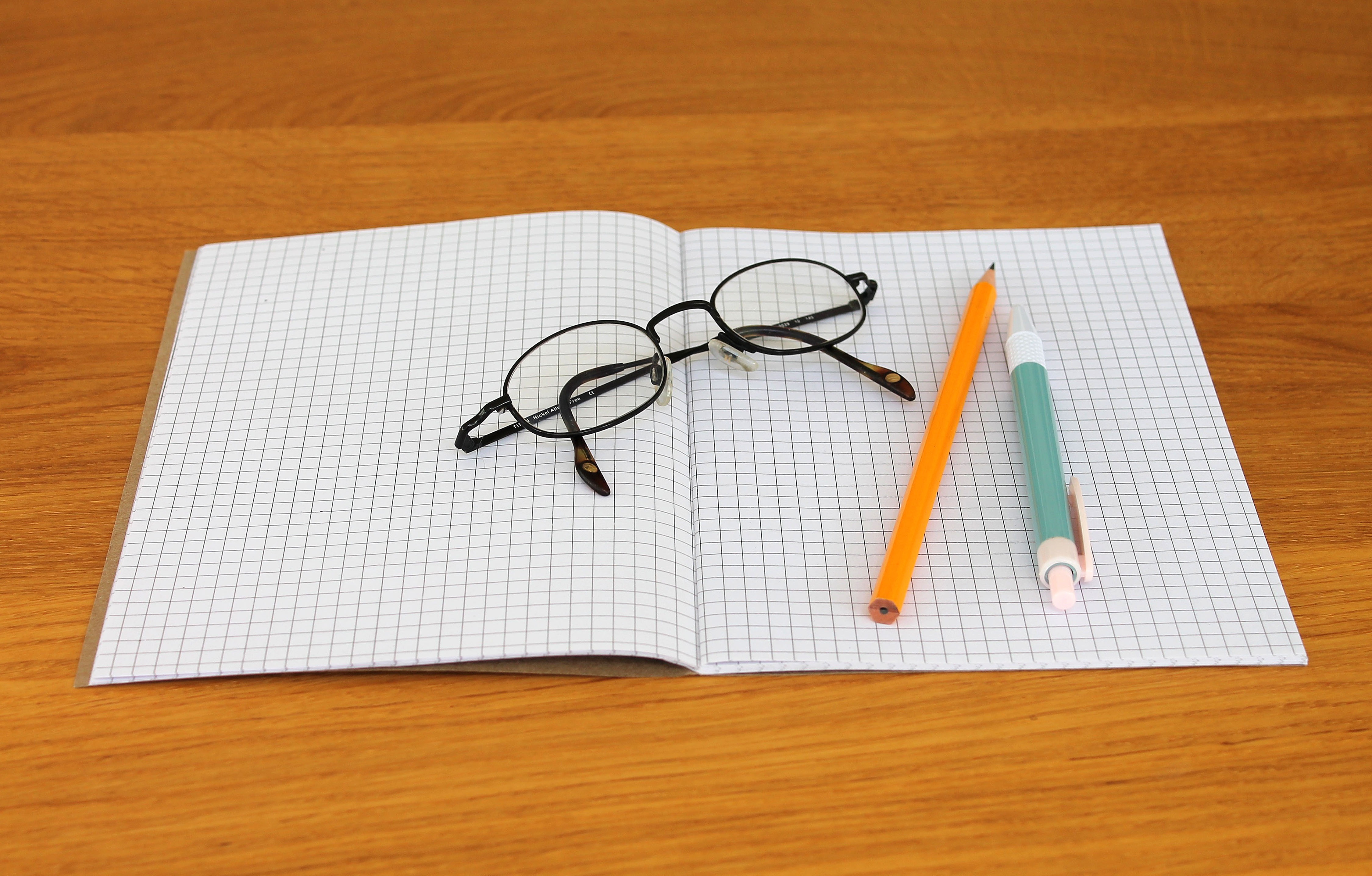 Una libreta, un bolígrafo y unas gafas para escribir