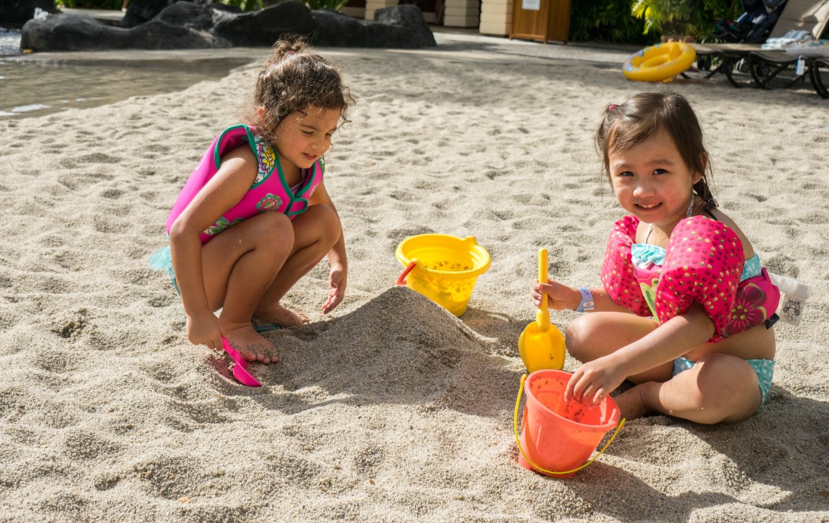 La imagen muestra dos niñas jugando en la playa.