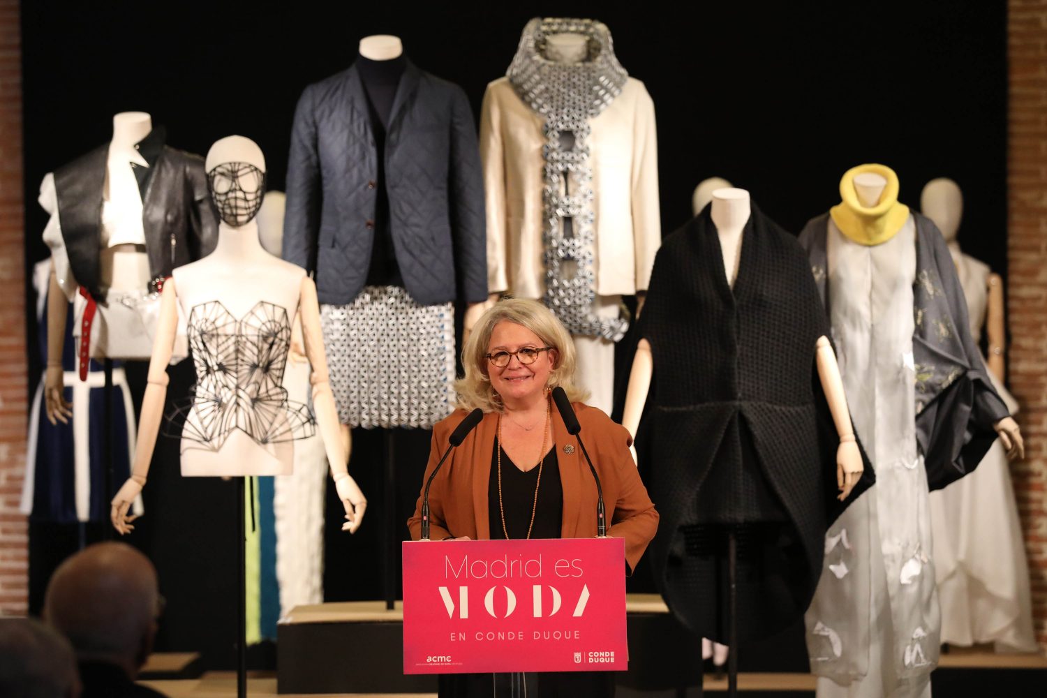 La imagen muestra una mujer presentando unos diseños de moda.