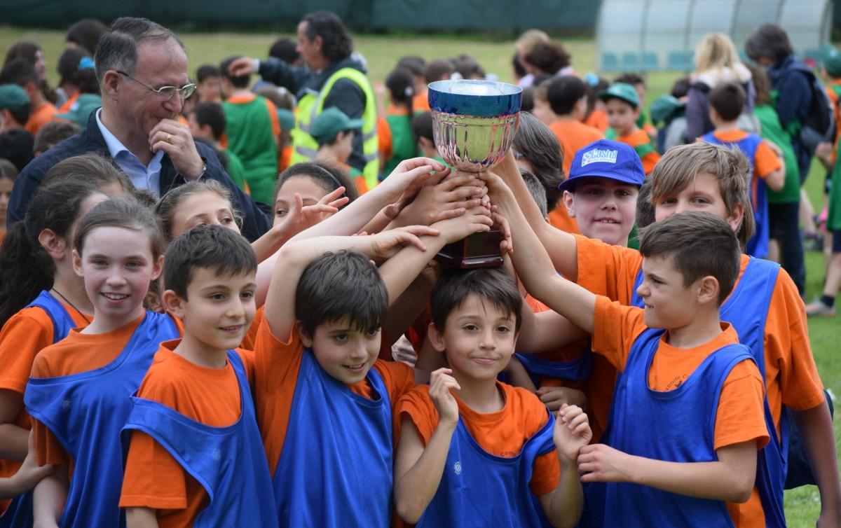La imagen muestra un grupo de niños y niñas que han ganado un trofeo.