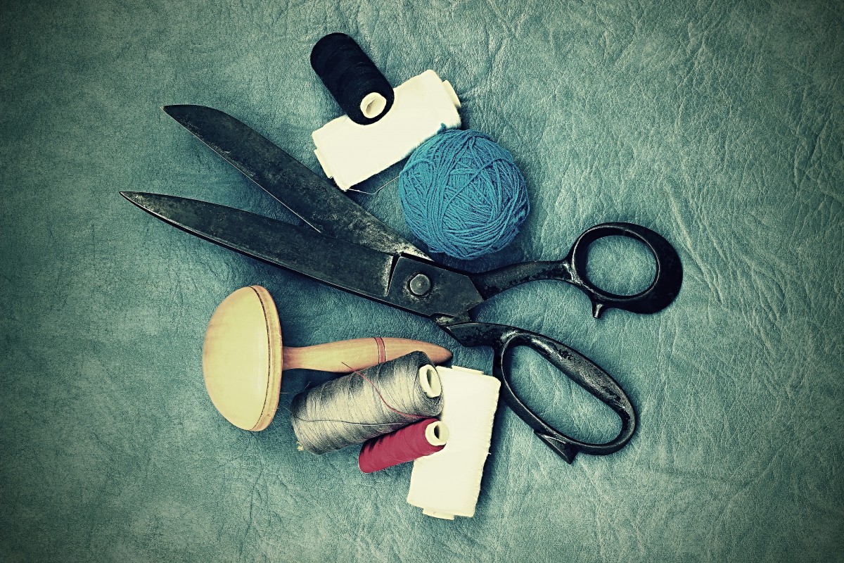 La imagen muestra diversos utensilios utilizados para coser, como aguja, hilo o tijeras.