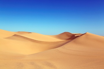 Paisaje de dunas de arena fina con un cielo azul de fondo