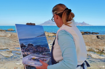 Mujer pintando sobre un lienzo un paiseje costero