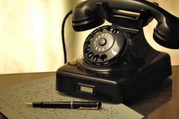 Teléfono antiguo negro sobre un papel con un bolígrafo