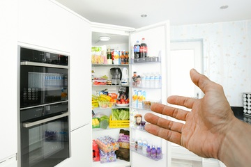 Imagen de una mano en primer plano mostrando un frigorífico abierto