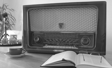 Aparato de radio antiguo con un libro abierto delante con unas gafas encima