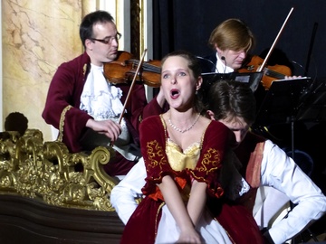 Una cantante de ópera y detrás unos violinistas