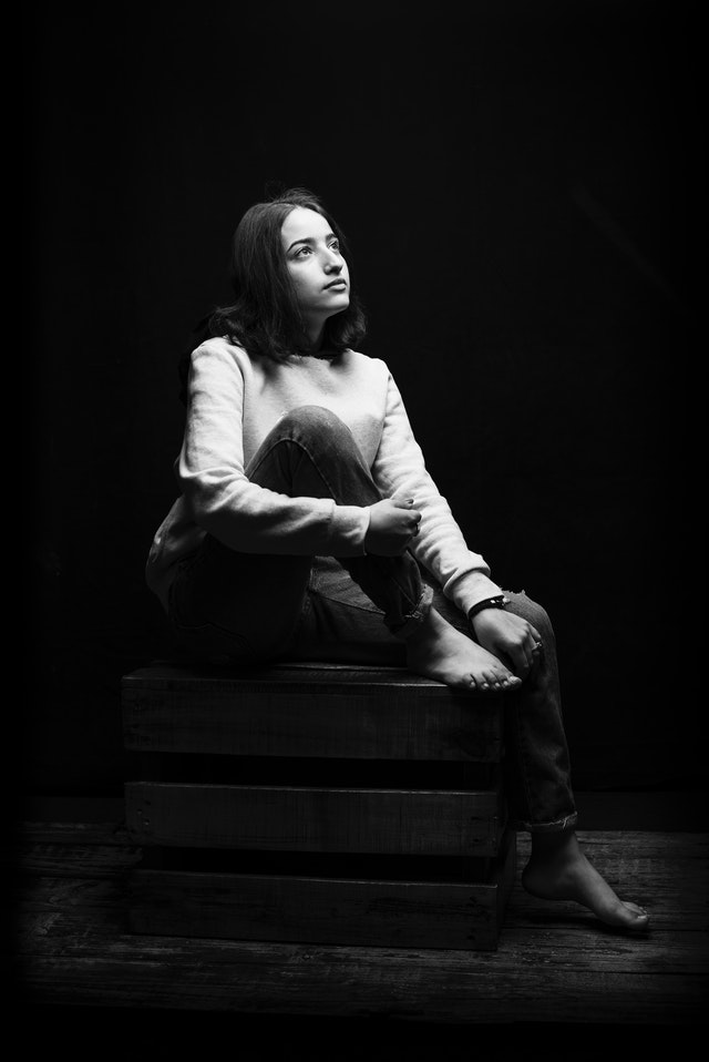 Imagen de una mujer sentada en una caja de madera mirando hacia arriba