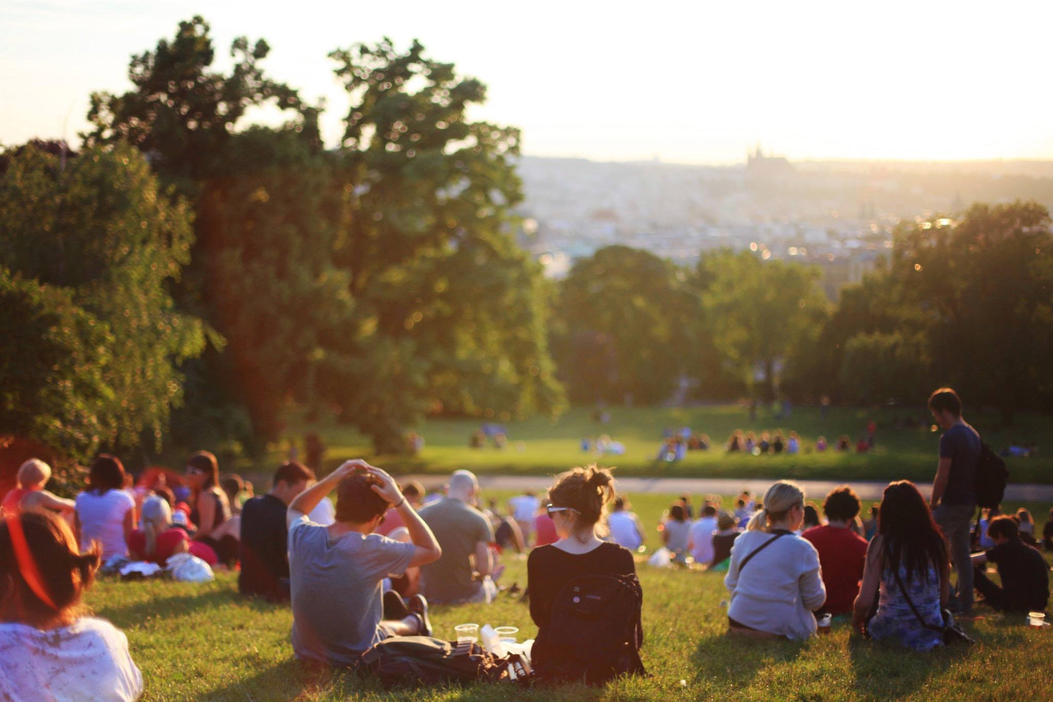 Personas sentadas en un parque viendo la puesta de sol.