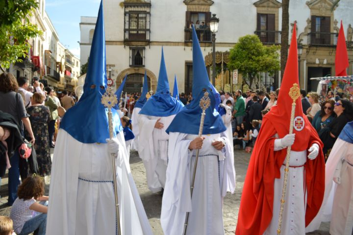 Foto de varios nazarenos con capirote azul y rojo.