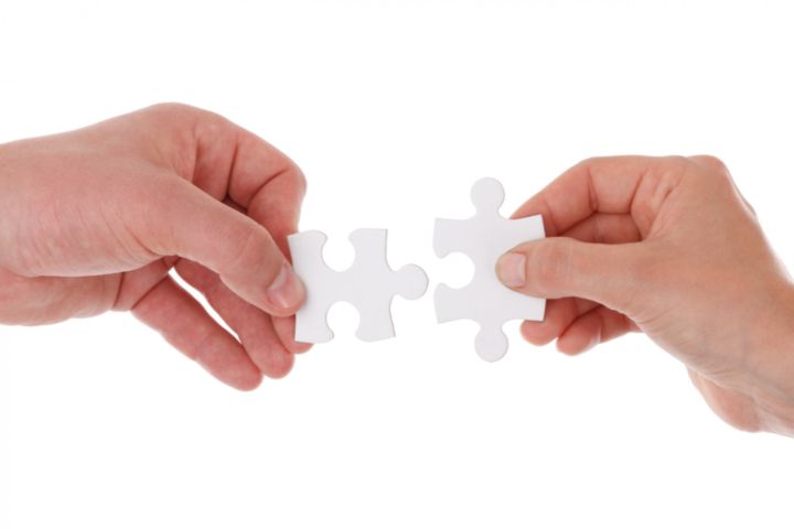 Dos manos uniendo piezas de puzzle.