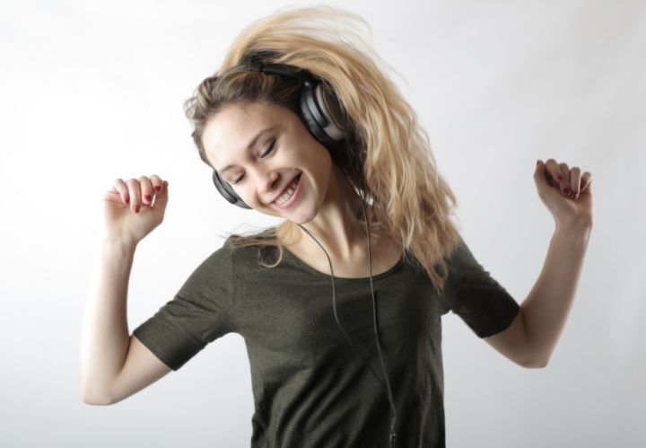 Chica sonriente con los brazos en alto escuchando música.