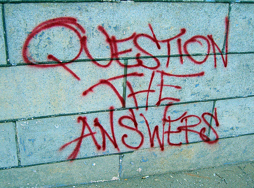 Grafiti en la calle con el lema "Question the answers", "cuestiona las respuestas"