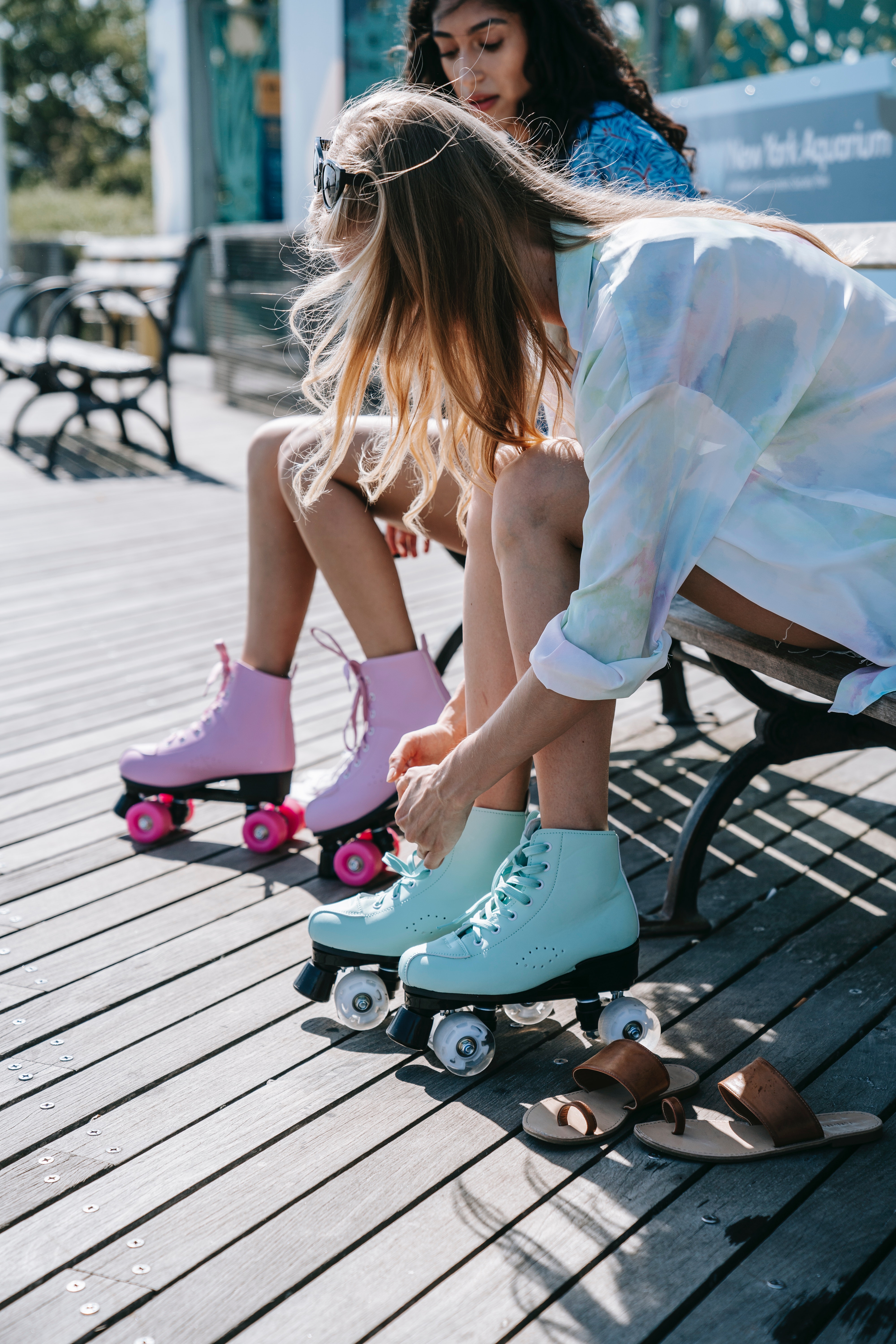 Dos chicas en un banco abrochándose los patines para patinar.