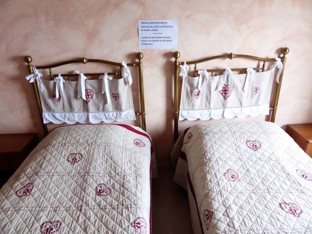 Esta imagen muestra dos camas con unas mantas de color blanco
