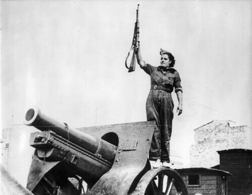Esta imagen muestra a una mujer con una arma en la mano encima de un tanque 