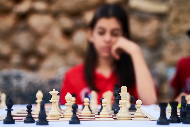La imagen muestra a una chica jugando al ajedrez.