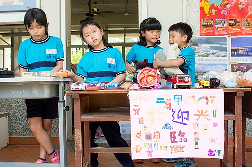 La imagen muestra a unos niños de colegio vendiendo en mesas escolares diferentes artículos.