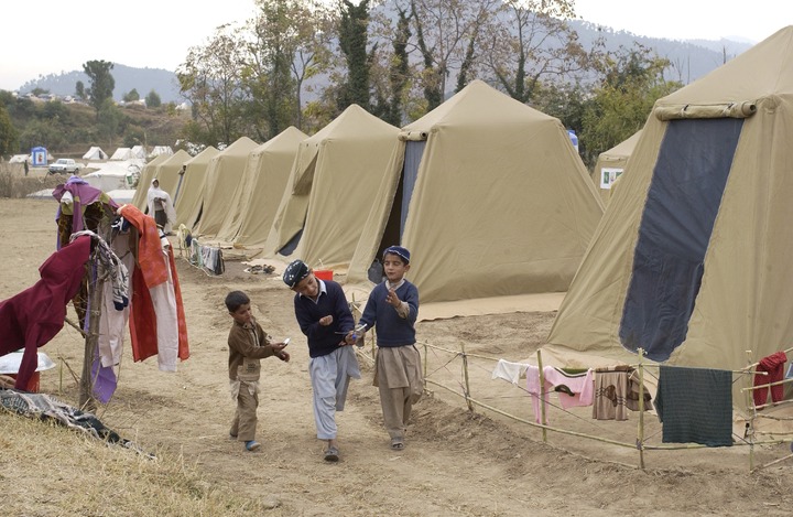 La imagen muestra a unos niños caminando por un campo de refugiados.