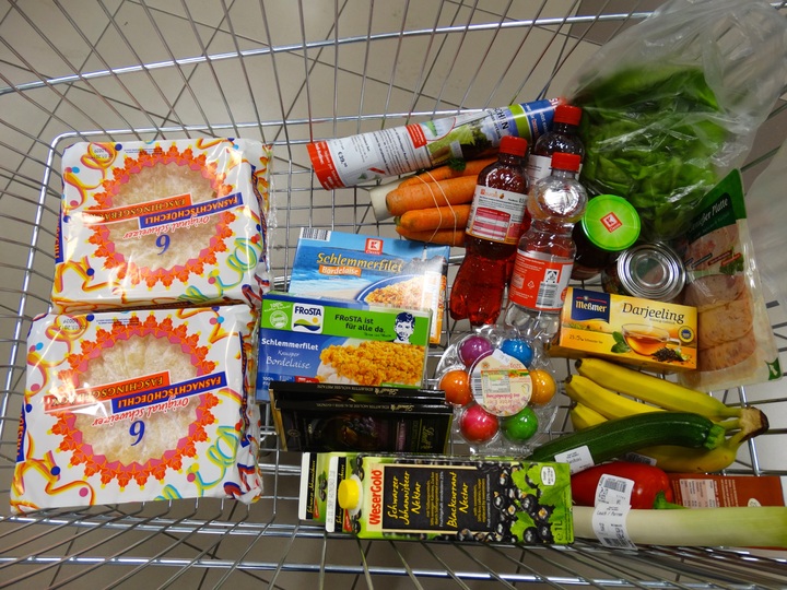 La imagen muestra un carrito de supermercado con productos de alimentación.