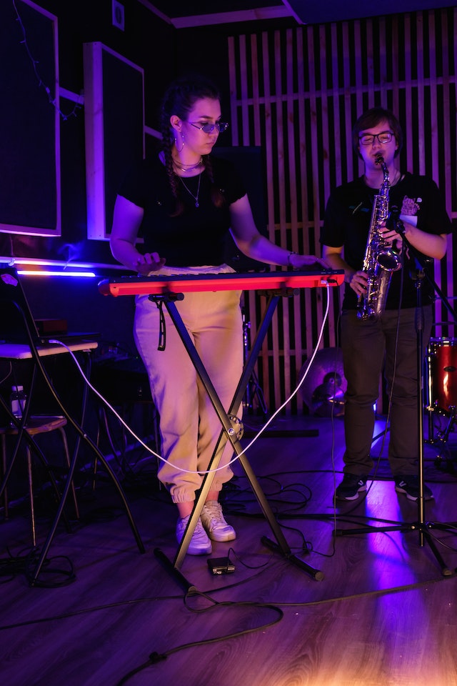 La imagen muestra a dos estudiantes tocando en una banda.