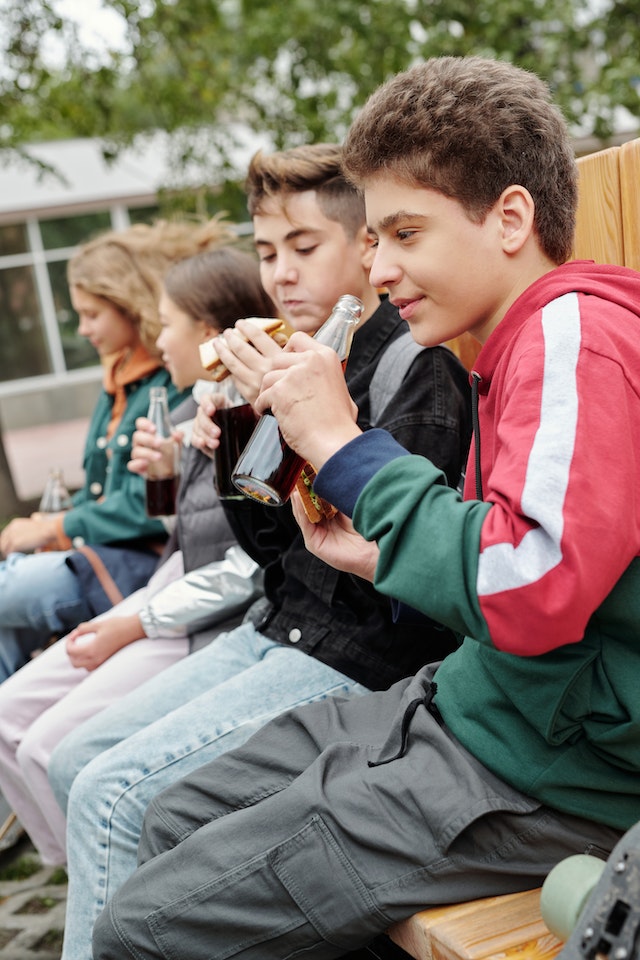 La imagen muestra a unos estudiantes desayunando en el patio del colegio.