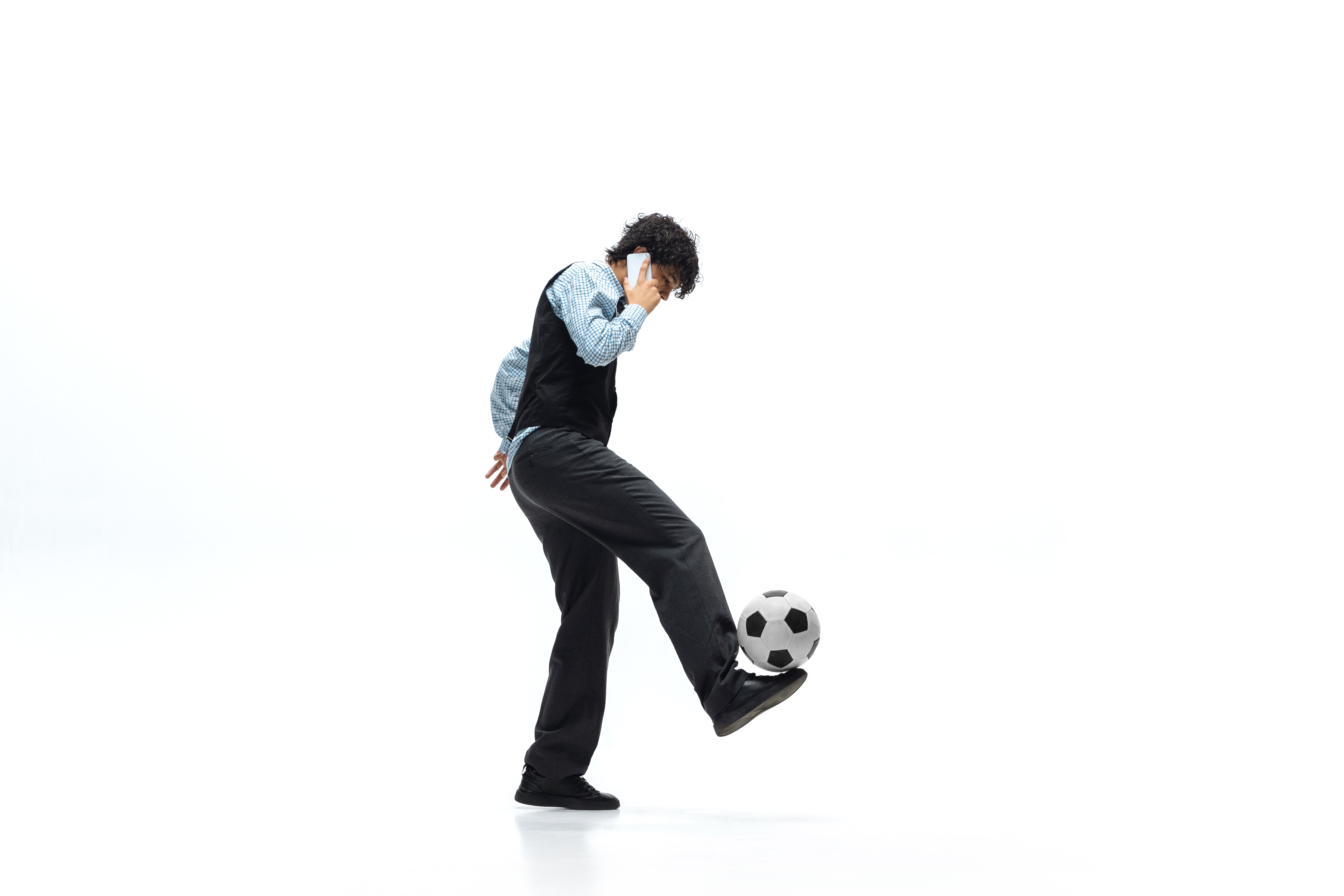 Hombre vestido con ropa arreglada hablando por teléfono y jugando al fútbol.