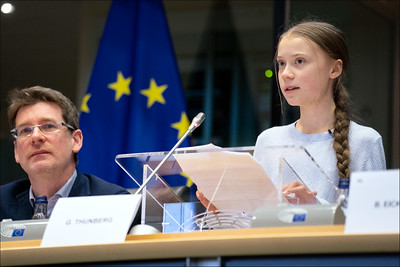 La imagen muestra a una niña que habla desde un atril y dirige la mirada al frente.