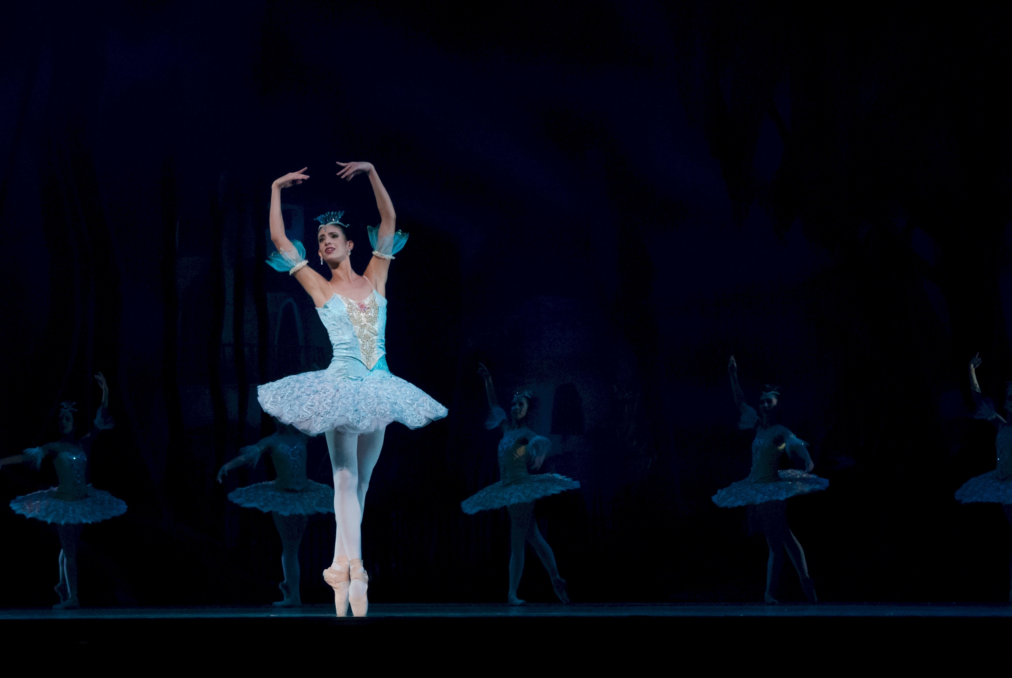 La imagen muestra a una bailarina en puntas y los brazos alzados