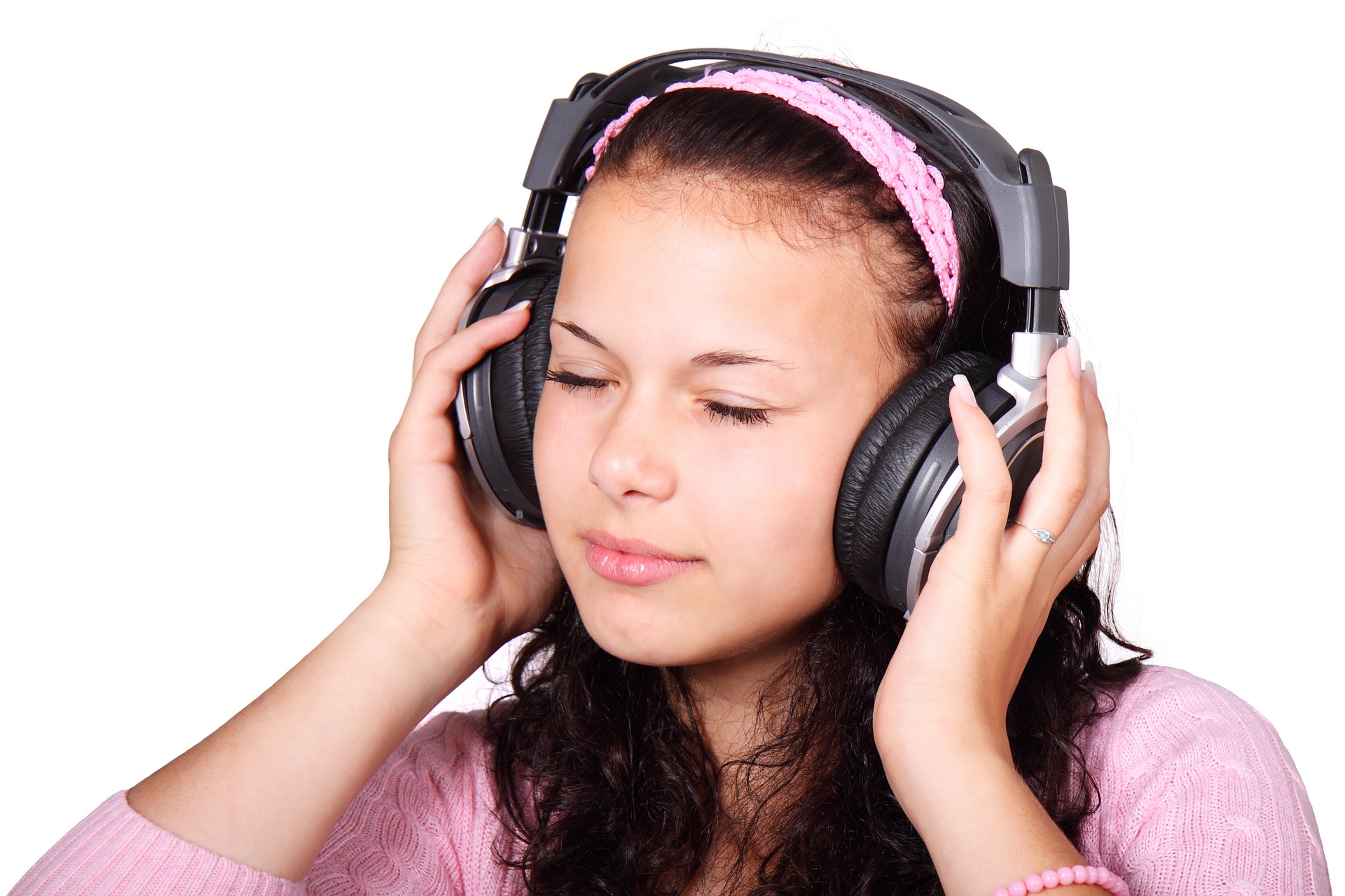 Mujer joven sujetando con sus manos unos cascos de música en la cabeza y cerrando los ojos