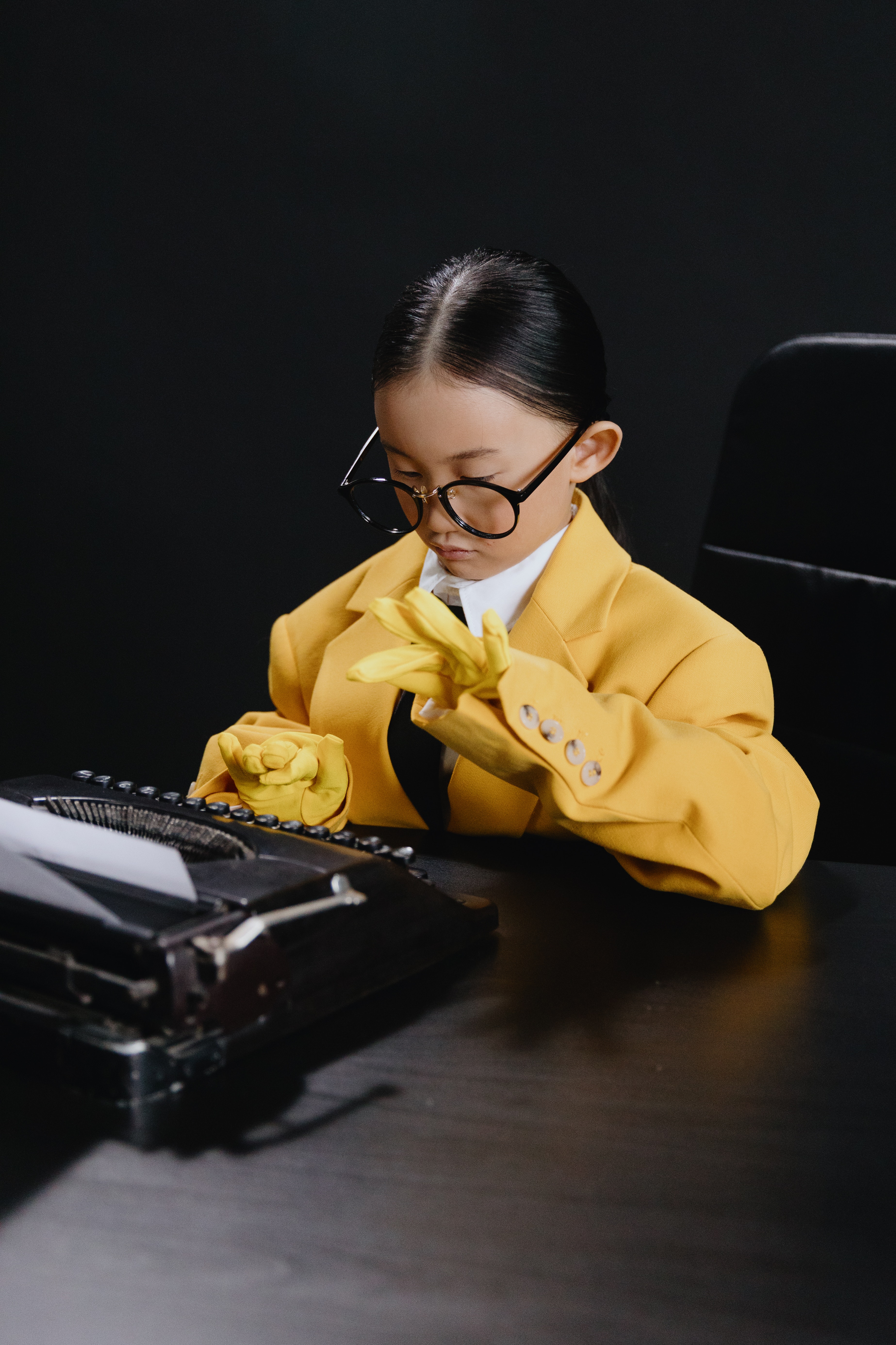 Una niña vestida de amarillo escribiendo en una máquina de escribir antigua