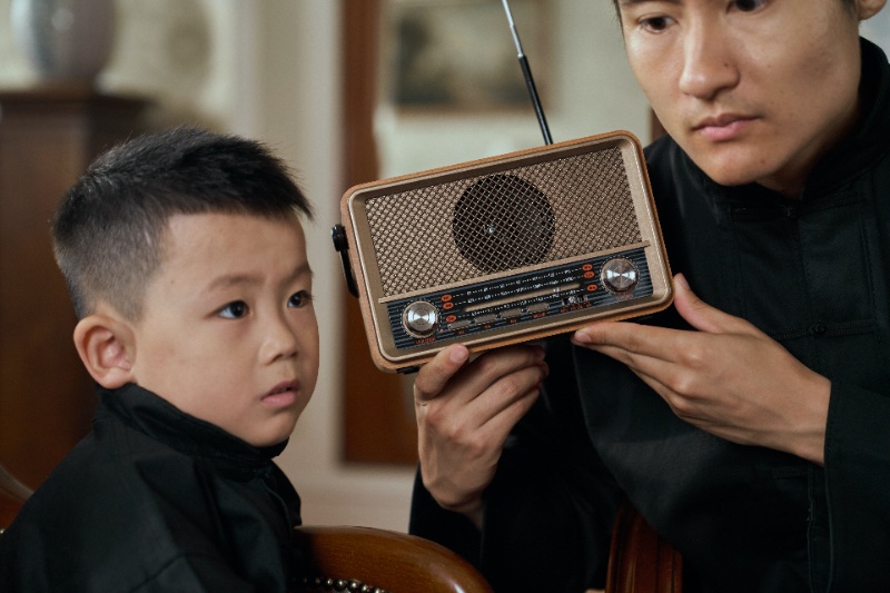 Un padre y un hijo escuchando una radio antigua.