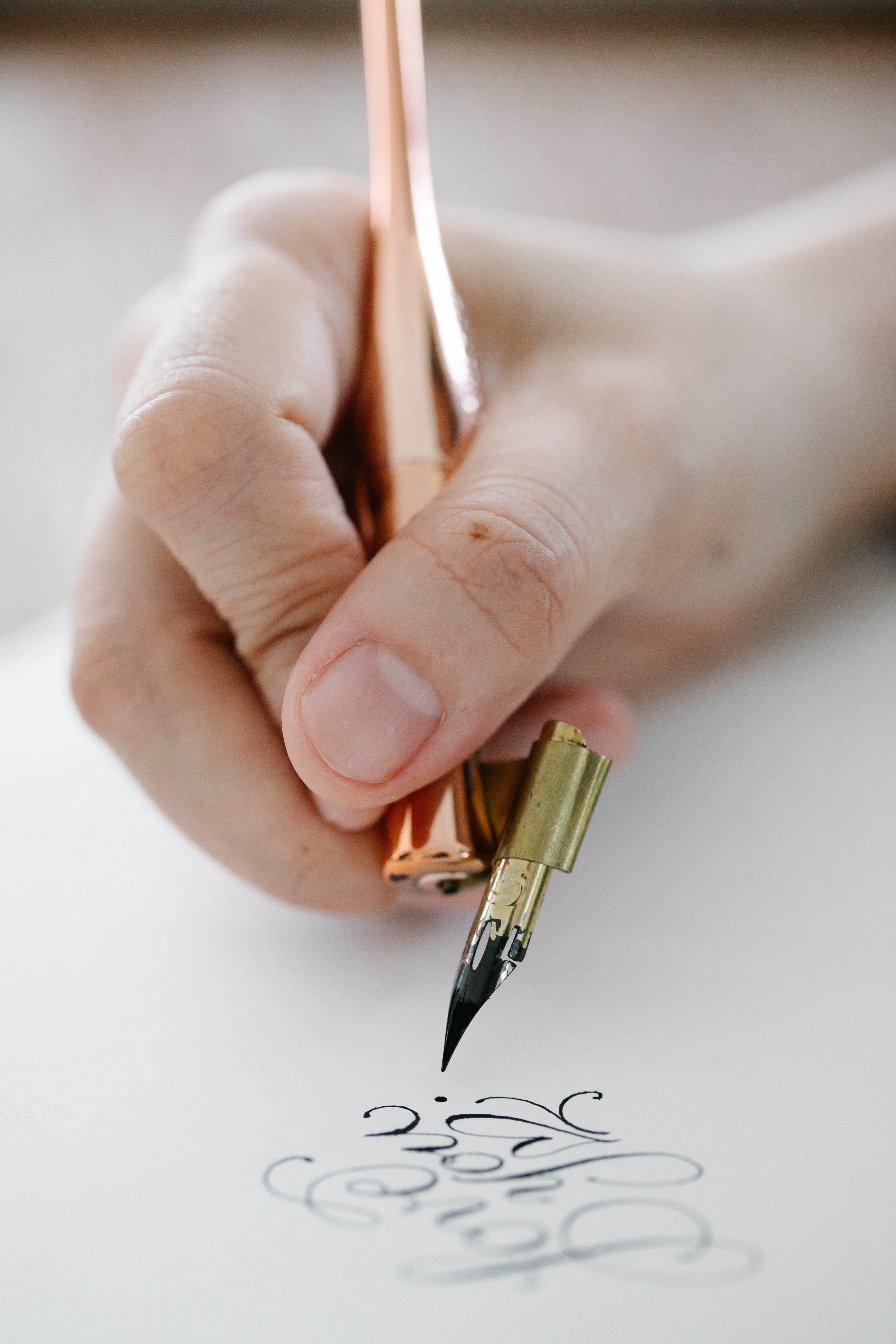 Una persona escribiendo con una pluma y dándole diferentes formas a las letras. 
