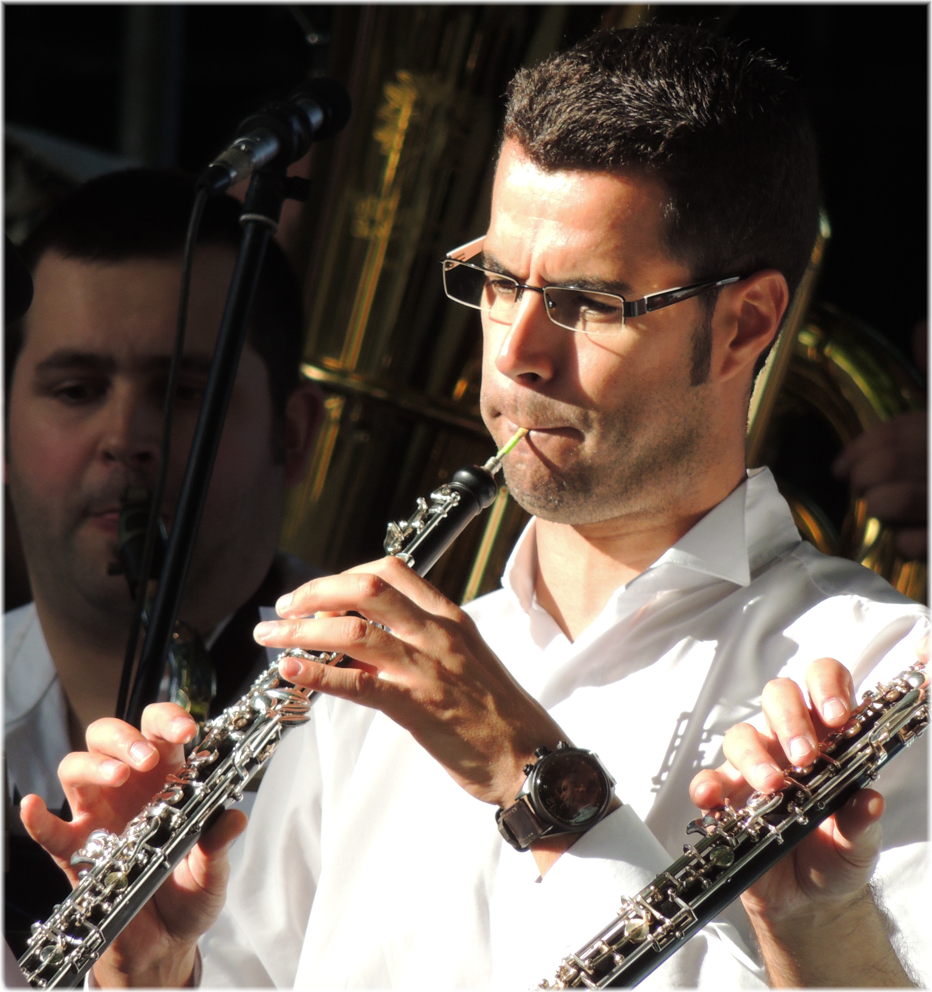 La imagen muestra a un hombre tocando el oboe en una orquesta.