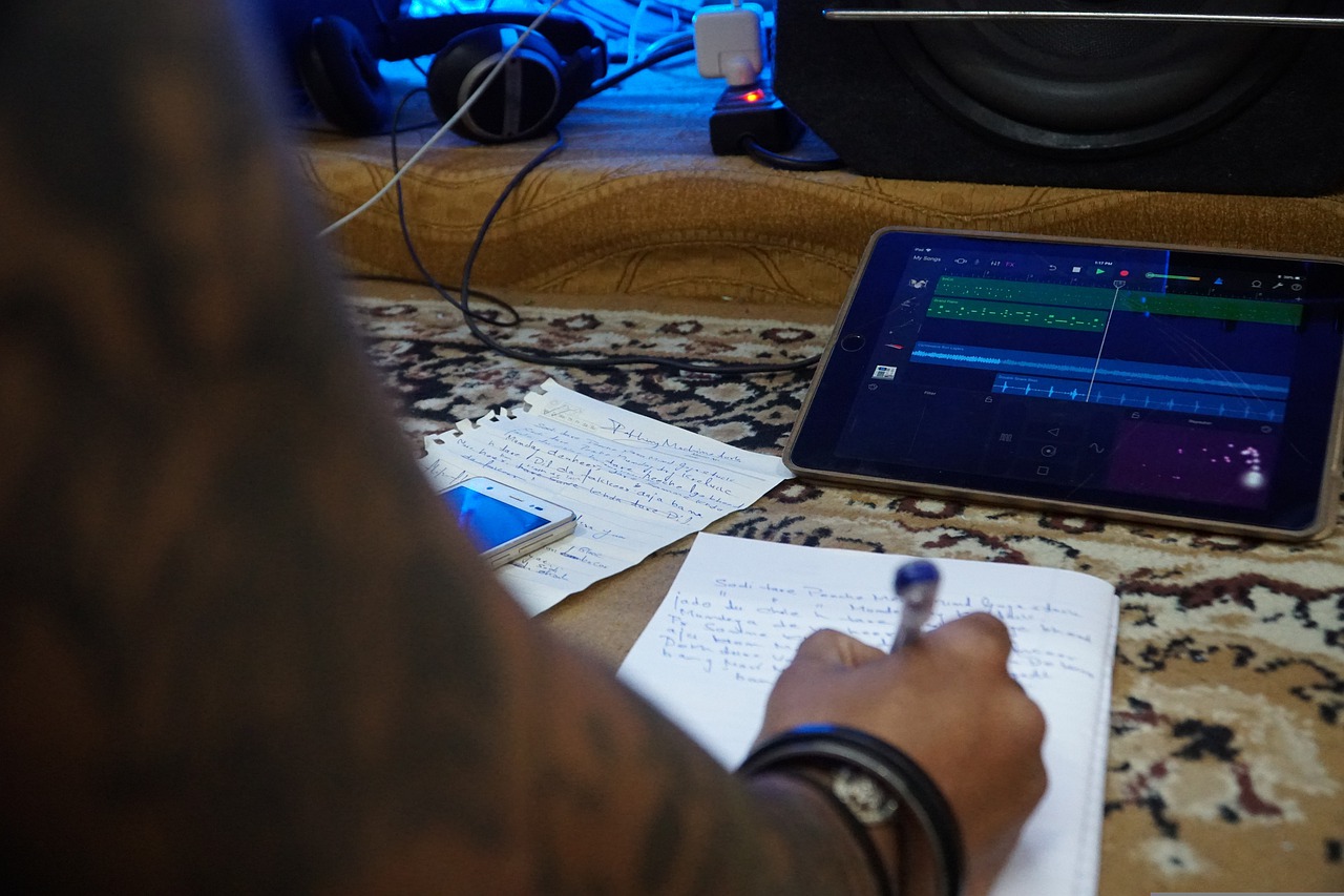 La imagen muestra una mano escribiendo y una tablet