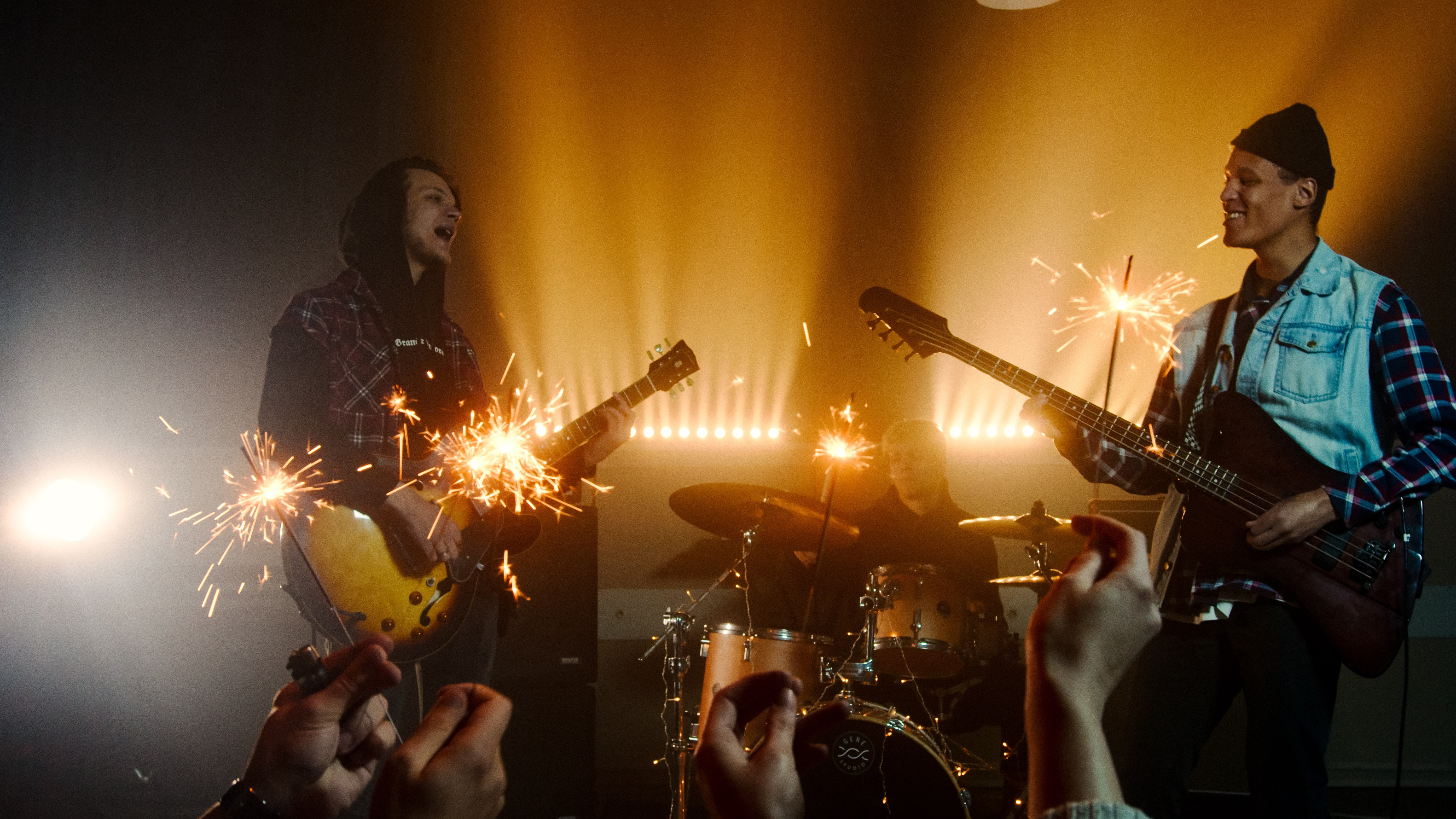 La imagen muestra a un guitarrista y a un bajista tocando en un concierto.