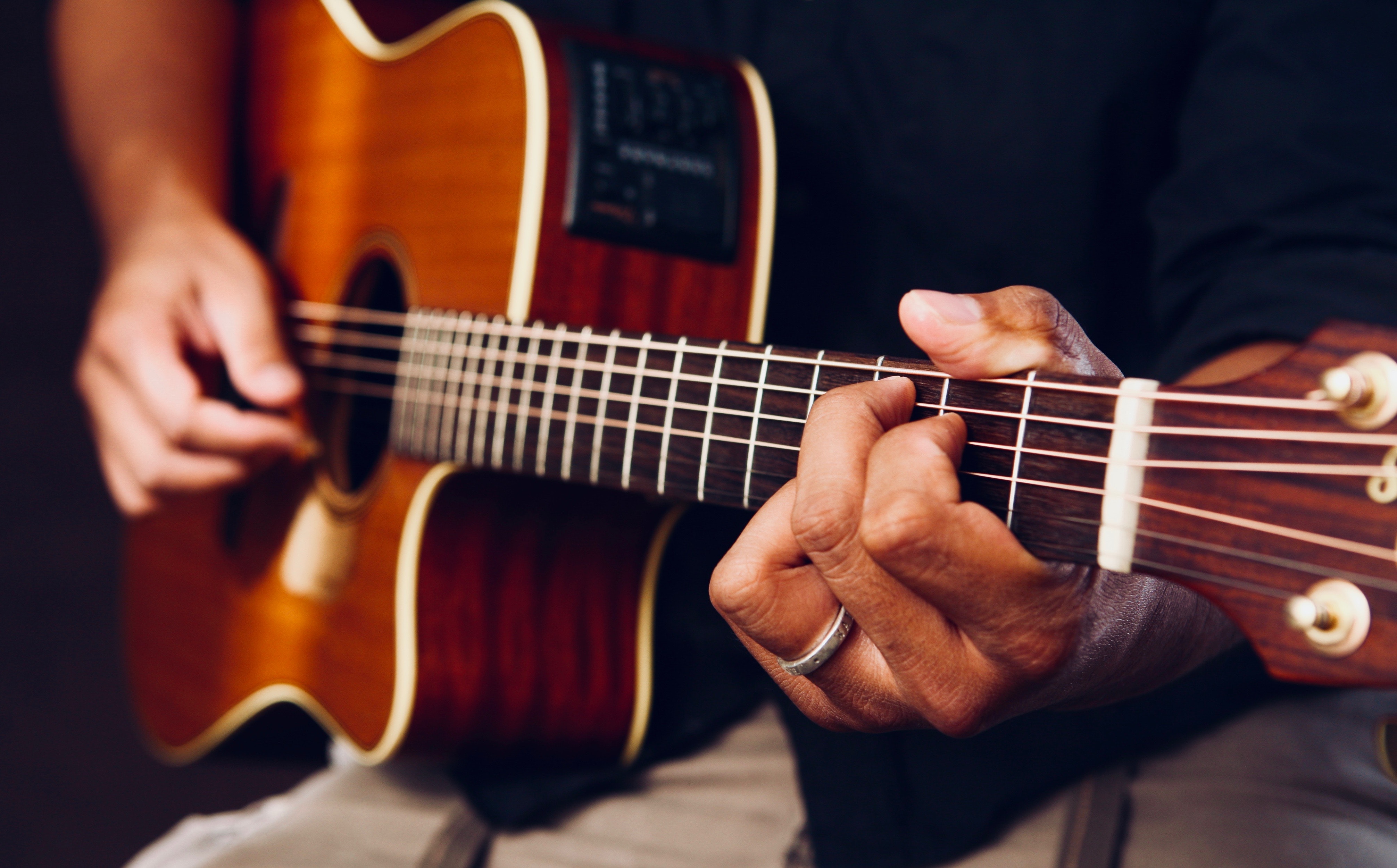 La imagen muestra a una persona tocando la guitarra acústica.