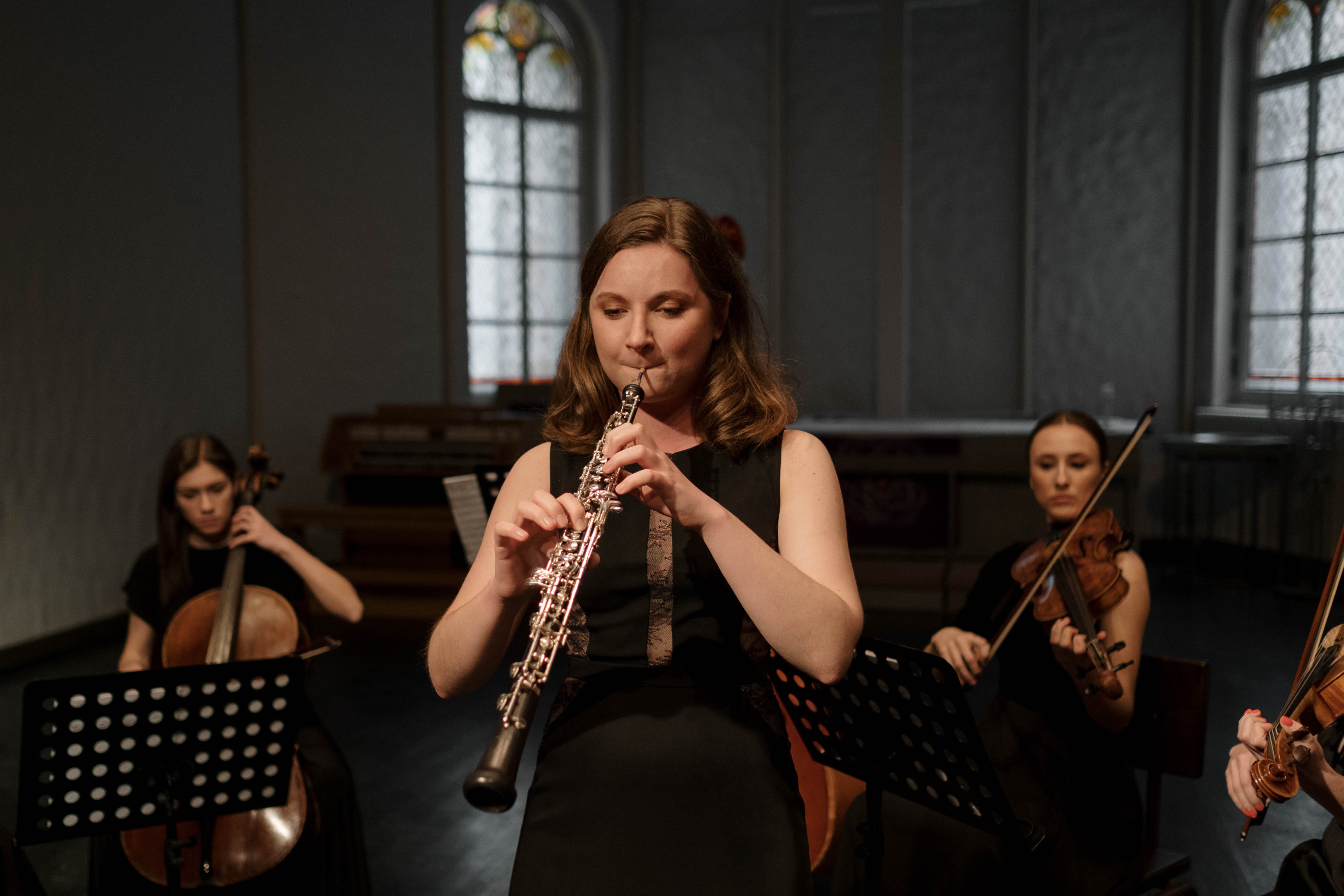 La imagen muestra a una mujer tocando el clarinete en un concierto.