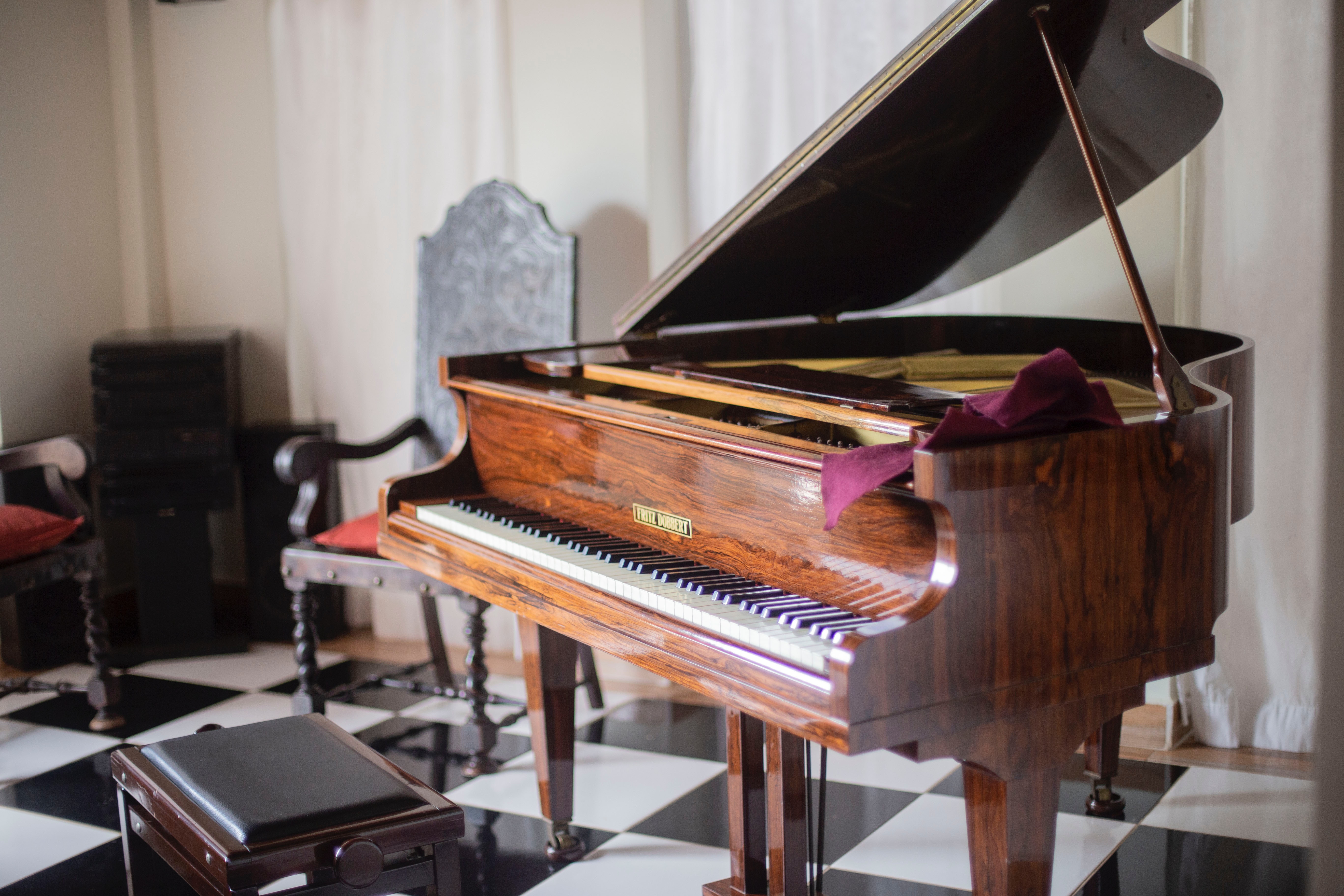 La imagen muestra un piano de cola de color marrón.