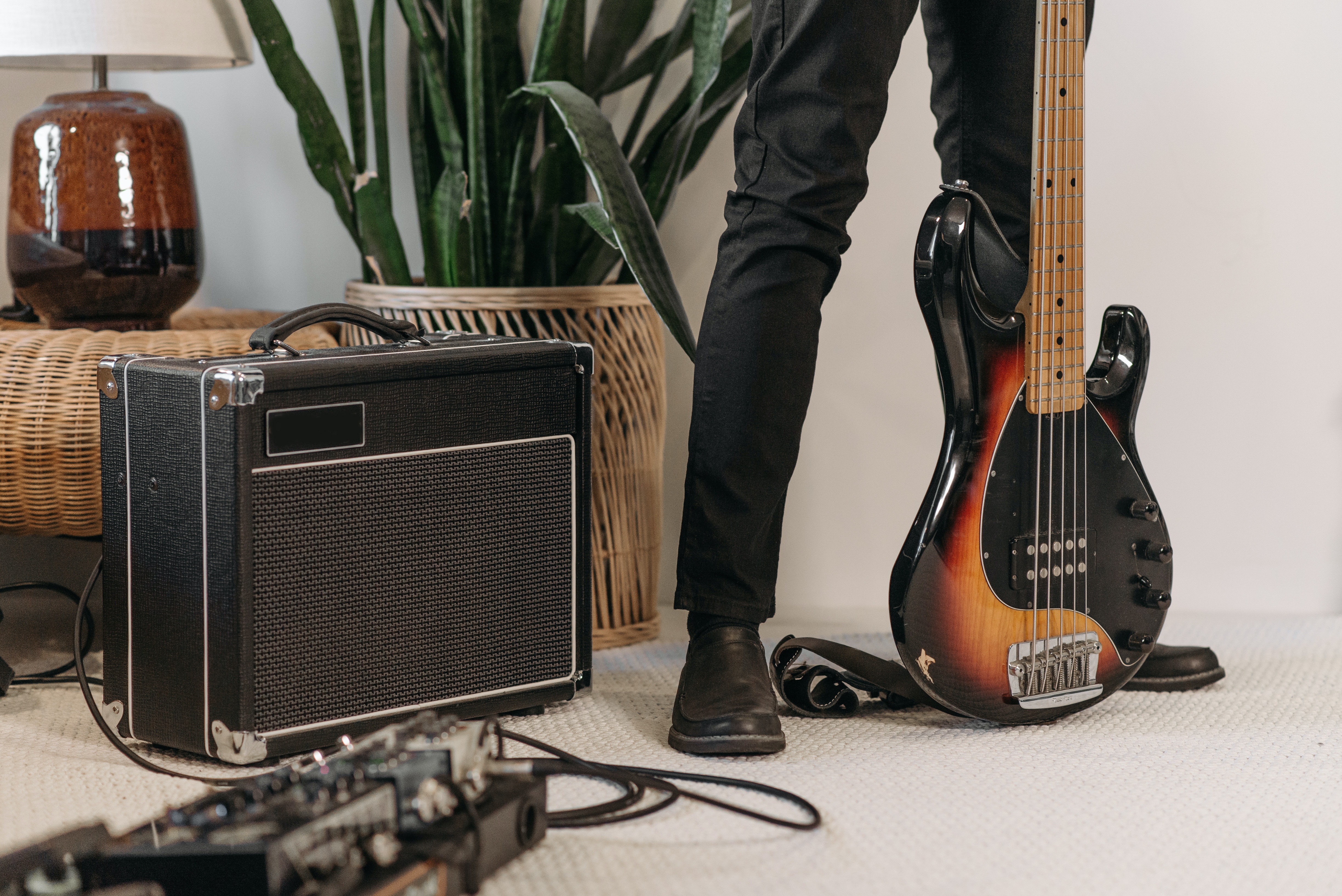 La imagen muestra unos pies al lado de una guitarra eléctrica y un amplificador.