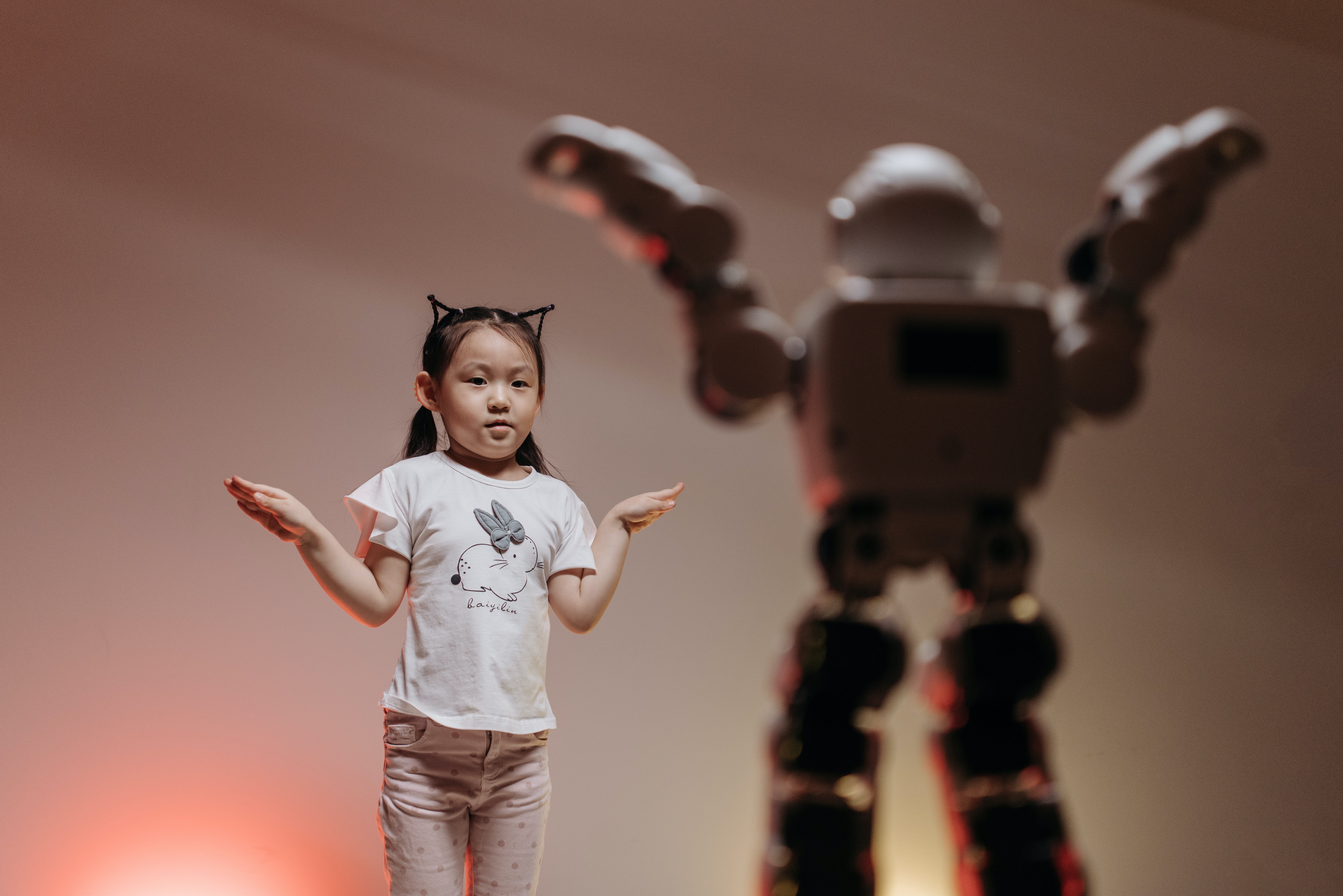 La imagen muestra una niña imitando a un robot