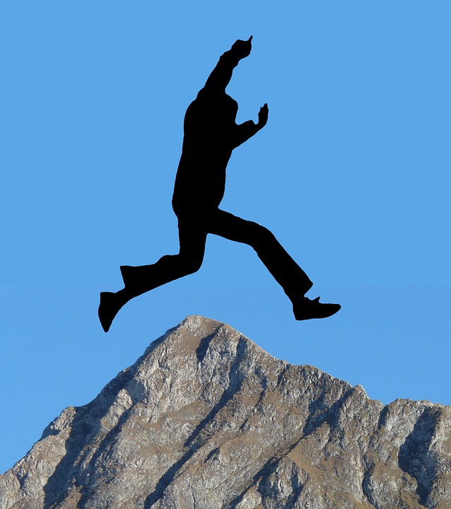 Silueta de una persona saltando sobre una montaña.