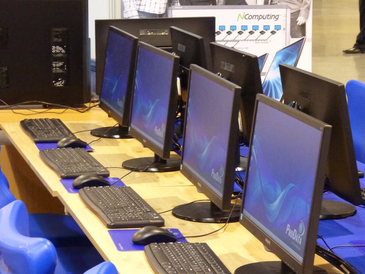La imagen muestra varios ordenadores encendidos en un aula.