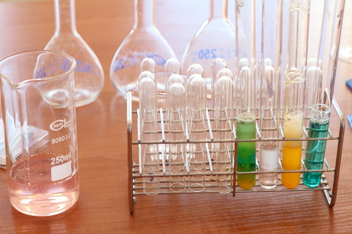 La imagen muestra tubos de ensayo, vasos y matraces en un laboratorio.