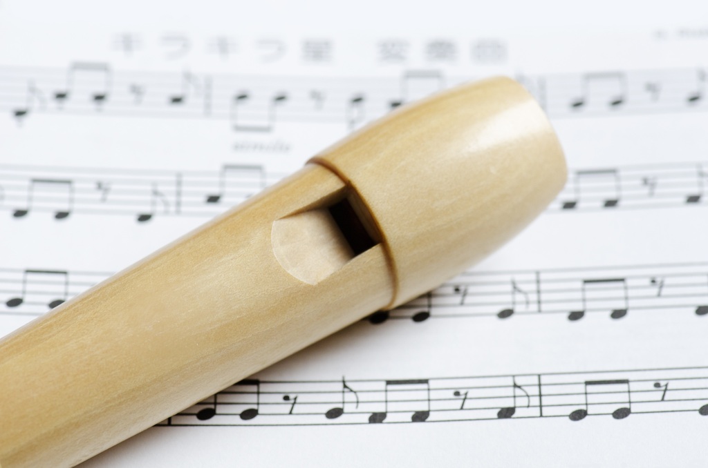 La imagen muestra una flauta dulce sobre una partitura.