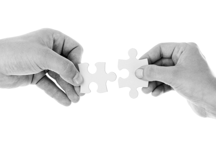 La imagen muestra dos manos sosteniendo cada una de ellas una pieza de un puzle que encajan la una con la otra perfectamente.