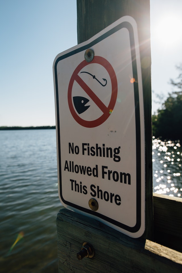 La imagen muestra un cartel de prohibido pescar.