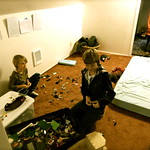  La imagen muestra Unos chicos ordenando un dormitorio que está muy desordenado.