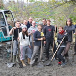 La imagen muestra a un grupo de voluntarios, con palas, trabajando en una zona campestre